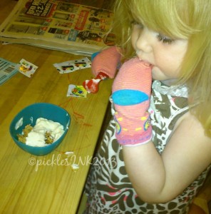 Toddler Molly eating cereal with socks on her hands.