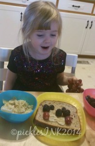 Child making her own snack out of bread, berries, grapes, and cheesy noodles.